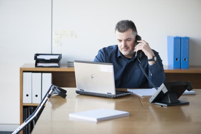 Un employé du Groupe SIFU travaillant avec un ordinateur portable et passant un appel